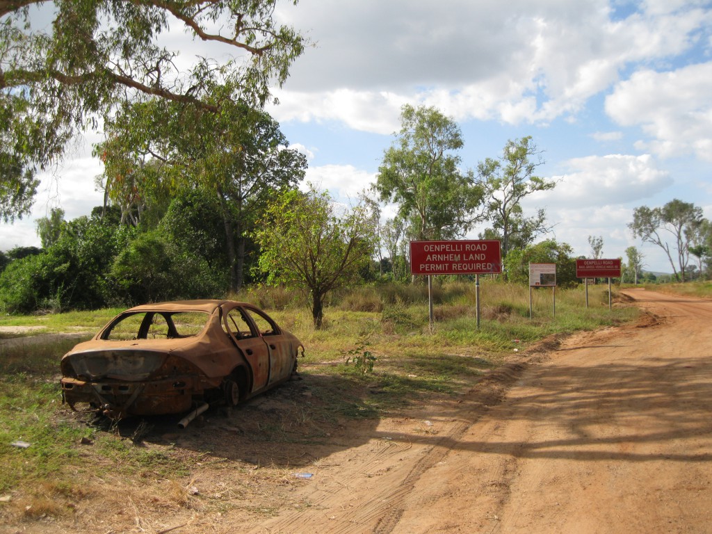 Burnt car and road signs at East Alligator River right at the border to Kakadu National Park on the Arnhem Land side